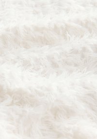 Tessuto bianco testurizzato caratterizzato da lunghe fibre morbide che creano un aspetto soffice, con leggere variazioni nello spessore e nella densità.