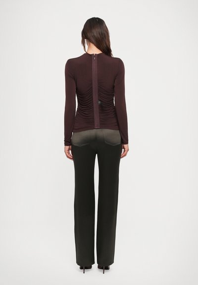 Long-sleeve, burgundy fitted top with gathered back detail, paired with black wide-leg trousers featuring subtle back pockets.