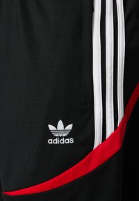 Černé sportovní šortky s červenými akcenty, bílým designem se třemi pruhy a vyšitým bílým logem Adidas na dolní levé straně.