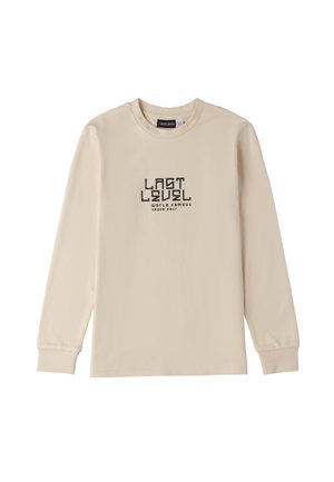 Maglietta a maniche lunghe beige in cotone con collo rotondo. Testo grafico nero centrato: "ULTIMO LIVELLO TOUR FEDELTÀ MONDIALE SKATE."