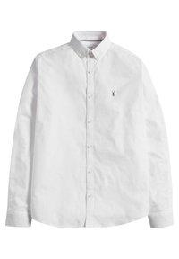 Chemise blanche à manches longues en coton. Elle présente un col classique, une fermeture à boutons et un petit logo sur le côté gauche.