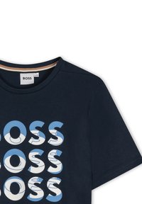 T-shirt in cotone blu navy con grande logo "BOSS" ripetuto in blu e bianco. Maniche corte e scollo rotondo con rifinitura interna a contrasto.