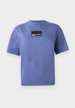 T-shirt azul de manga curta com um emblema retangular preto centrado no peito que diz "KARL LAGERFELD JEANS."