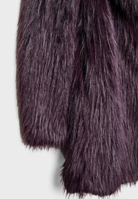 Sztuczne futro w głębokim purpurowym kolorze z długim, gęstym włosem. Miękka faktura i puszysty wygląd. Krawędź charakteryzuje się czystym, prostym cięciem.