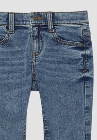 Jeans in denim con un lavaggio blu scolorito, caratterizzati da un design a cinque tasche, cuciture arancioni e una chiusura a bottone metallico in vita.