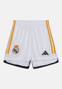 Pantalones cortos deportivos blancos con rayas laterales amarillas, que presentan el logo del Real Madrid y un logo bordado negro de Adidas en el dobladillo.