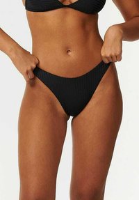 Zwarte geribbelde bikini onderkant met een low-rise snit, met een gladde textuur en minimalistisch design. Accentueert de lichaamshouding.