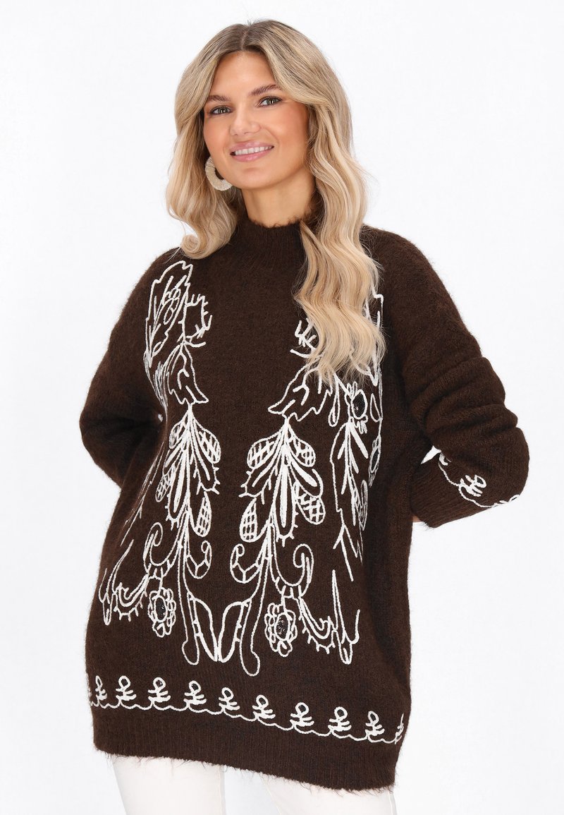 Pulover tricotat maro cu broderie florală albă, guler înalt, mâneci ample și modele decorative la margine. Textură moale, design casual.