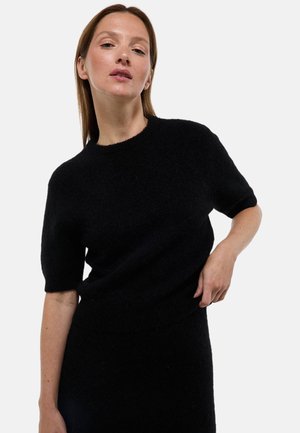 Pull en tricot noir à manches courtes et col rond. Tissu doux et texturé avec un ourlet côtelé, associé à une jupe noire assortie.