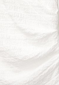 Tessuto bianco testurizzato con un motivo increspato, morbido e leggero, caratterizzato da una leggera irregolarità nella superficie e nella profondità.