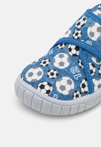 Blå tyg slip-on sko dekorerad med svart och vitt mönster av fotbollar. Texturerad gummisula, elastiska remmar för en säker passform.