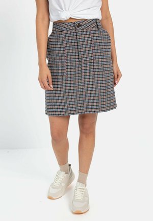 Geruite rok met een aansluitende taille, twee zakken en een zoom boven de knie. Kleuren zijn blauw, roze en wit op een donkere achtergrond.