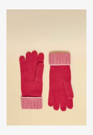 Paar rote Strickhandschuhe mit pink-rot gestreiften Bündchen, flach auf einer beigen Oberfläche liegend, Vorder- und Rückseite sichtbar.