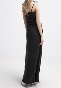 Sort, udenærmet maxi kjole med en tætsiddende overdel, afslappet talje og justerbare stropper. Glat, let stof med en flydende silhuet.