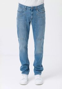 Jeans in denim azzurro chiaro caratterizzati da una vestibilità rilassata, due grandi tasche anteriori e chiusura con bottone. Abbinati a sneakers bianche.