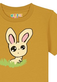 Geel t-shirt met een cartoonkonijn met grote ogen en roze binnenoren, gedeeltelijk verborgen door groen gras aan de onderkant.