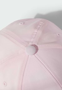 Růžová baseballová čepice s hladkým povrchem, opatřená kulatým špičkou, ventilačními otvory a ladícím vrchním knoflíkem. Švy jsou viditelné podél švů.