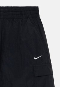 Črne lahke kratke hlače z elastičnim pasom, stranskim žepom in belim Nike logotipom spredaj. Teksturirana tkanina.
