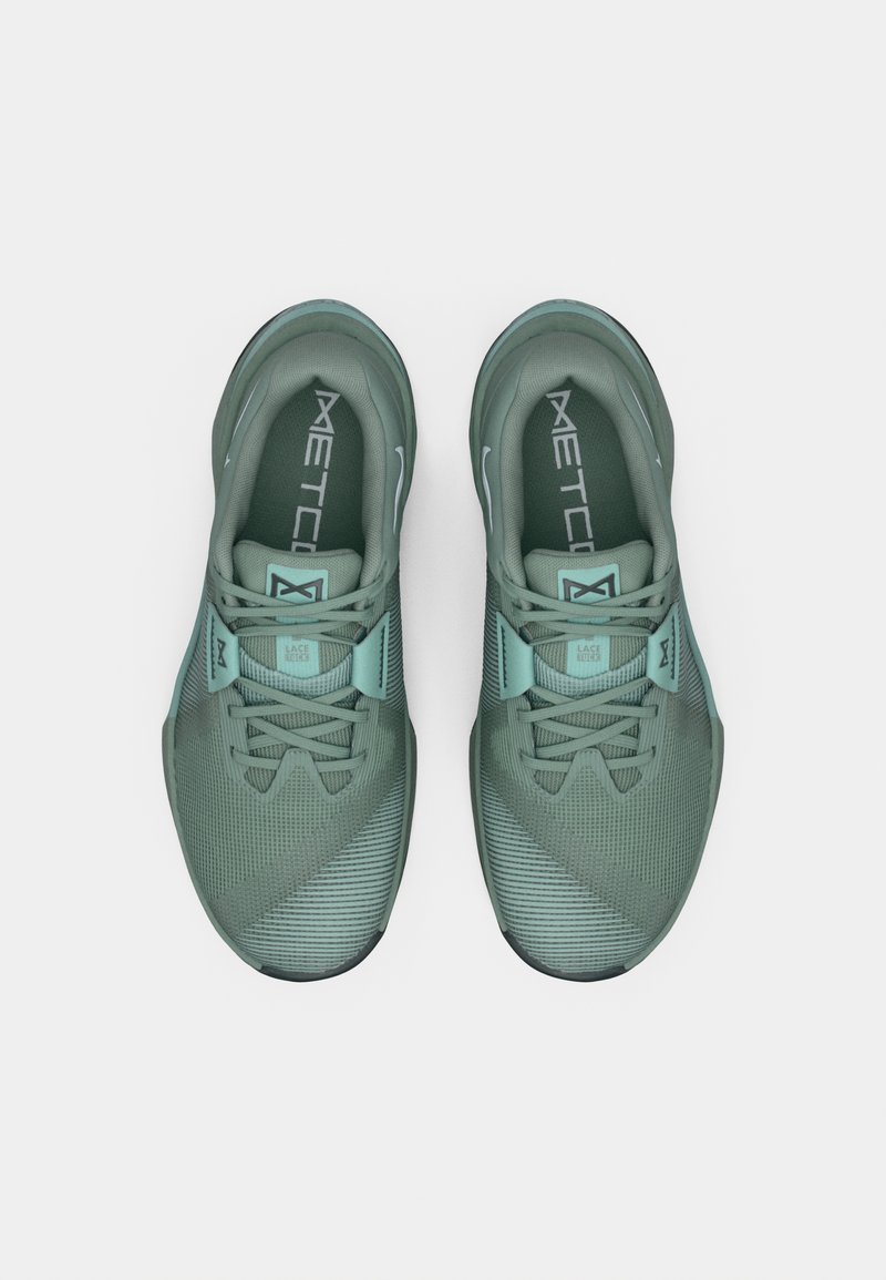 Zapatillas deportivas verdes con parte superior de tela texturizada, detalles de malla y acentos turquesa. Cuentan con un diseño de cordones y una suela redondeada.