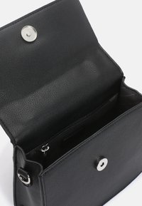 Sac en cuir noir au fini texturé, fermeture à pression magnétique et poche intérieure zippée. Forme rectangulaire compacte.