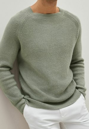 Lichtgroene ribgebreide trui met een ronde hals en lange mouwen, met een relaxte pasvorm en een gestructureerde stof. Gecombineerd met witte pantalons.