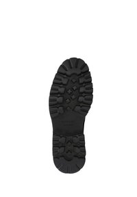 Suela de zapato de goma negra con un patrón de banda de rodadura robusto y clavos multidireccionales; "WITCHEN hecho a mano" grabado cerca del arco.