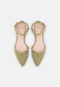 Flats en daim vert à bout pointu avec une bordure ornée de clous dorés et une bride à la cheville. Intérieur rose avec un logo de marque.