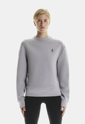 Hellblaues Sweatshirt aus weichem Stoff, mit klassischem Rundhalsausschnitt, langen Ärmeln und einem kleinen schwarzen Logo auf der Brust.