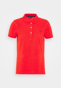 Polo shirt rossa in cotone. Presenta un colletto, una patta con tre bottoni e un piccolo logo ricamato sul petto. Maniche corte.