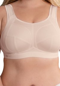 Bra sportivo beige realizzato in tessuto testurizzato con spalline larghe e regolabili, caratterizzato da un design seamless e pannelli di supporto rinforzati.