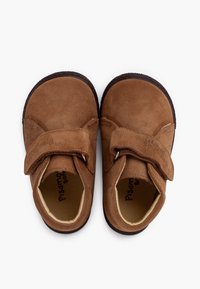 Chaussures en daim marron avec une sangle en Velcro. Bout rond et doublure intérieure douce. Semelles en caoutchouc robustes avec un détail texturé pour une meilleure adhérence.