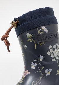 Botte de pluie en caoutchouc florale de couleur bleu marine foncé, avec un col en tissu texturé, un laçage en cuir ajustable et un logo en relief.