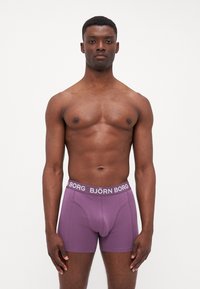 Purple boxer briefs with a white "BJÖRN BORG" waistband, made of soft fabric, featuring a snug fit and stitching details on the legs.