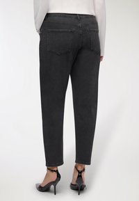 Czarne dżinsy z prostymi nogawkami, tylnymi kieszeniami i nieco spłowiałym wykończeniem. W zestawieniu z błyszczącymi czarnymi szpilkami.