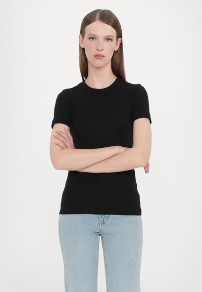 Black short-sleeve top with a round neckline, made from a smooth fabric, paired with light blue high-waisted jeans. Simple design.