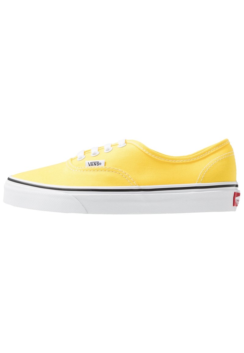 Žluté plátěné tenisky s bílými tkaničkami a gumovou podešví. Mají černý lem podél podešve a malé logo Vans na boku.