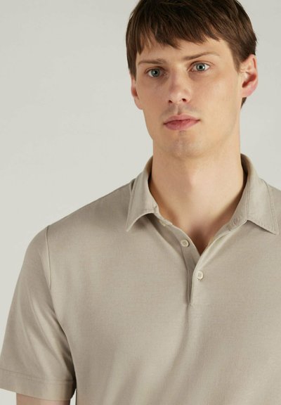 Korte mouw polo in lichtbeige met een zachte textuur, voorzien van een knoopsluiting en een klassiek kraagontwerp.