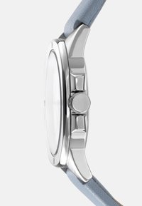 Zilveren polshorloge met een ronde kast, heldere glas, en een lichtblauwe lederen band. Beschikt over een opvallende zijknop en een gladde afwerking.