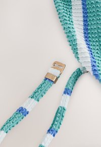 Tissu tricoté rayé vert, blanc et bleu avec une boucle métallique couleur or attachée à l’extrémité d’une lanière.