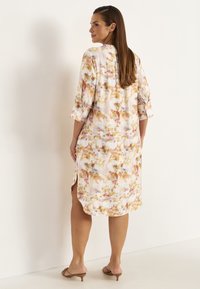 Blumenmuster-Kleiderhemd in pastellfarbenen Tönen von Rosa, Gold und Creme. Mit langen Ärmeln und hochrollbaren Riegeln sowie seitlichen Schlitzen für mehr Bewegungsfreiheit.