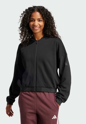Schwarze Zip-Up-Jacke mit hohem Kragen und geripptem Saum, die einen lockeren Schnitt hat und Akzentdetails an den Ärmeln aufweist.