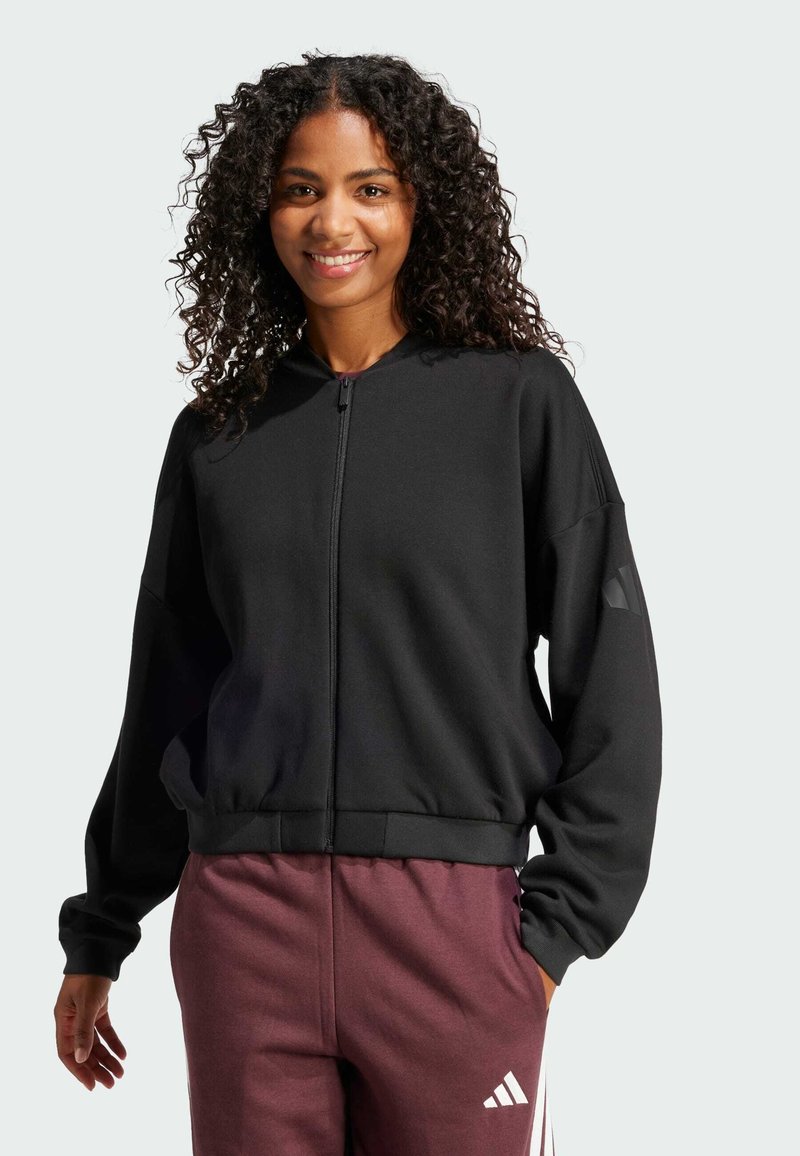 Sudadera negra con cremallera y cuello alto, con un dobladillo con canalé, que presenta un corte relajado y detalles de acento en las mangas.