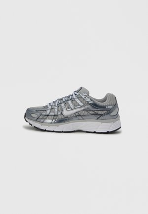 Grijze en zilveren Nike P-6000 sneaker met mesh- en lederen details, witte middenzool, zwarte buitenzool en Nike swoosh aan de zijkant.