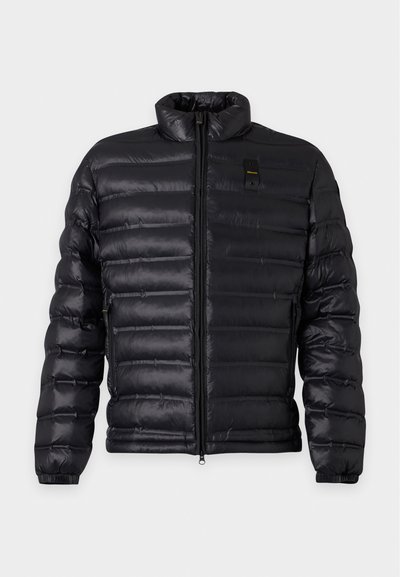 Veste matelassée noire avec col montant, fermeture éclair à l'avant, poches latérales et poignets élastiques, présentée sur un fond clair uni.