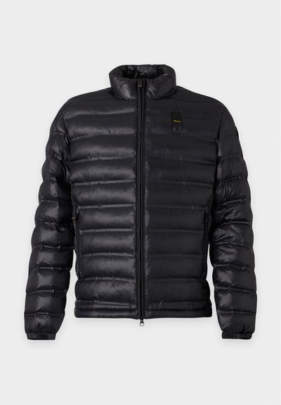 Veste matelassée noire avec col montant, fermeture éclair à l'avant, poches latérales et poignets élastiques, présentée sur un fond clair uni.