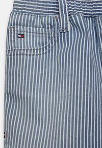 Striped blue and white fabric featuring a front pocket with logo detail. Soft texture with a lightweight, casual design.