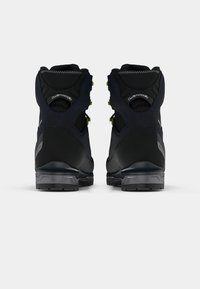 Botas de caminhada em preto e azul marinho com tecido texturizado, solas de borracha e detalhes em amarelo. Apresentam colarinhos acolchoados e copos de calcanhar reforçados.