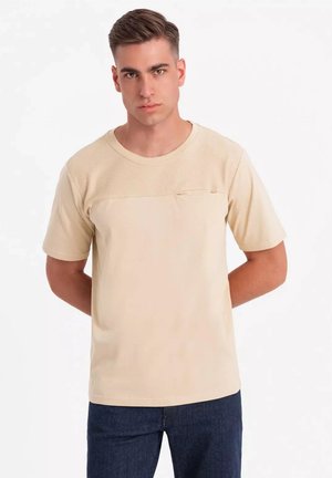 Beige Kurzarm-T-Shirt mit strukturiertem Oberteil und kleiner Brusttasche. Glattes Material, runder Ausschnitt, locker geschnitten.