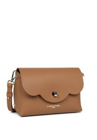 Borsa a tracolla in pelle tan con patta ondulata, hardware argentato e tracolla regolabile. Presenta un marchio impresso sul davanti. Design compatto.