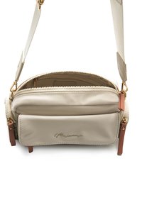 Beige Umhängetasche mit goldfarbenen Beschlägen, Reißverschluss und einer Vordertasche. Verfügt über eine glatte Textur und verstellbaren Riemen.